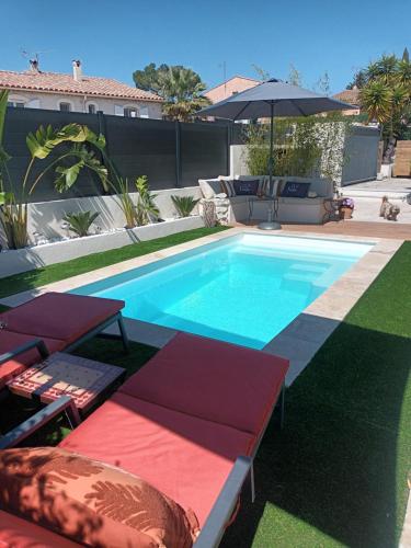 une piscine avec deux chaises longues et un parasol dans l'établissement Jolie villa Lalou Côte d'Azur trois chambres, à Fréjus