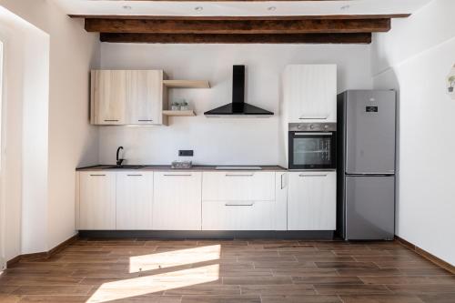 a kitchen with white cabinets and a refrigerator at Giano Host - Gozzano, Simple Pleasures in Genova