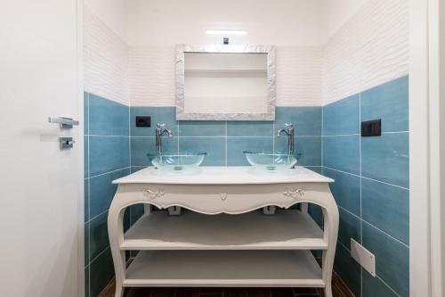 a bathroom with two sinks and blue tiles at Giano Host - Gozzano, Simple Pleasures in Genova