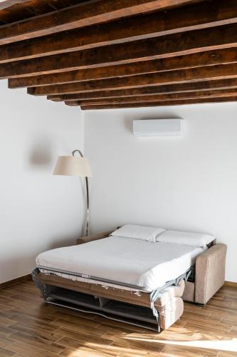 a bed in a room with a white wall at Giano Host - Gozzano, Simple Pleasures in Genova