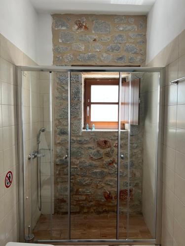 a glass shower in a bathroom with a stone wall at Koukouri Village in Kafióna