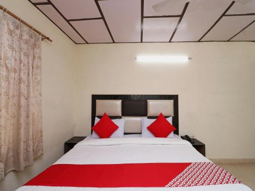 a bedroom with a large bed with red pillows at Hotel O Country Lodge in Dharamshala