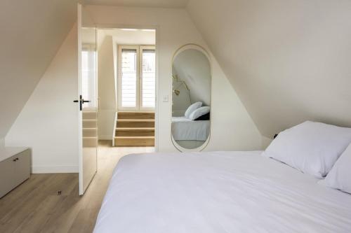 Un dormitorio con una gran cama blanca y un espejo. en Apartment Hoorn Center Original - extended stays by Haring Verhuur, en Hoorn