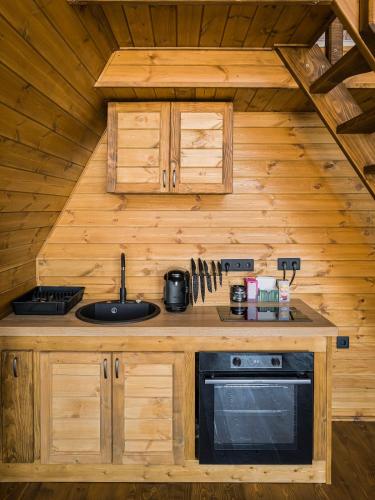 a kitchen in a wooden cabin with a stove at A Way To Nature in Măgura