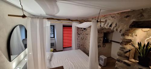 - une chambre avec un mur en pierre et un lit avec des rideaux dans l'établissement Gîte de village 2p, terrasse de toit et jacuzzi privatif, à Aubignas