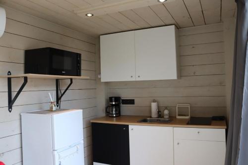a small kitchen with white cabinets and a refrigerator at Uniek privé natuurdomein voor 14 personen in Evergem