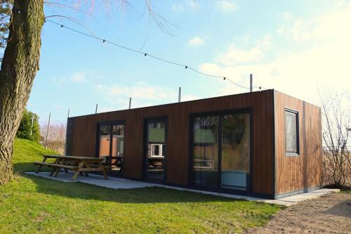 a small cabin with a picnic table and a tree at Uniek privé natuurdomein voor 14 personen in Evergem