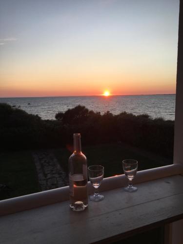 - une bouteille de vin et deux verres sur un balcon avec vue sur le coucher du soleil dans l'établissement Villa face à la mer avec vue exceptionnelle, à Pénestin