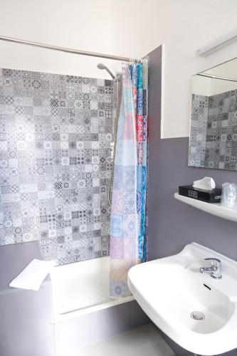 a bathroom with a sink and a shower curtain at easy&cosy-Hotel Moers-Mitte in Moers