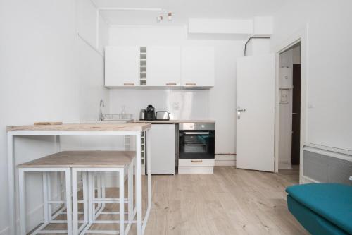 une cuisine avec des armoires blanches et un comptoir dans l'établissement Appartement Moderne et Équipé aux Portes de Paris, à Aubervilliers