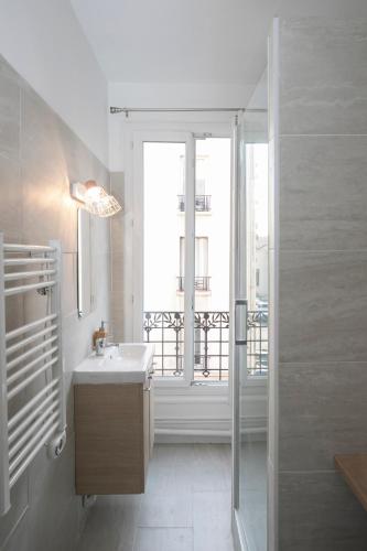 une salle de bain avec un lavabo et une fenêtre dans l'établissement Appartement Moderne et Équipé aux Portes de Paris, à Aubervilliers