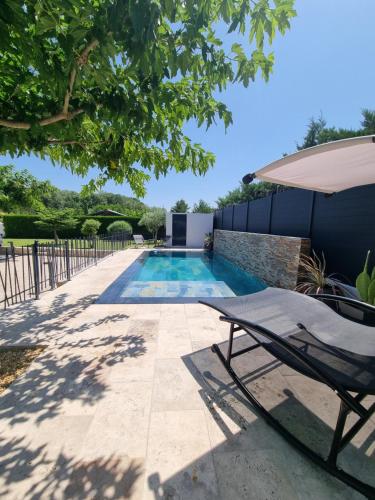 - une piscine avec une chaise longue et un parasol dans l'établissement Maison du Luberon, à Maubec