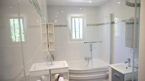 La salle de bains blanche est pourvue d'une baignoire, d'un lavabo et d'une baignoire. dans l'établissement Mas Provencal 8 pers, air-conditioned private pool, à Antibes