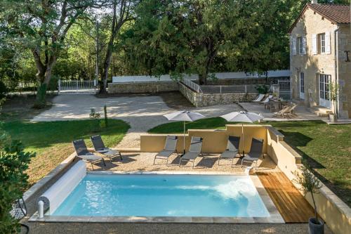 - une piscine avec des chaises, une table et un parasol dans l'établissement Gite Côté Truffes, à Les Palissoux