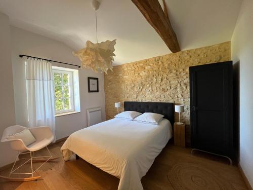 une chambre avec un lit blanc et une chaise dans l'établissement Gite Côté Truffes, à Les Palissoux