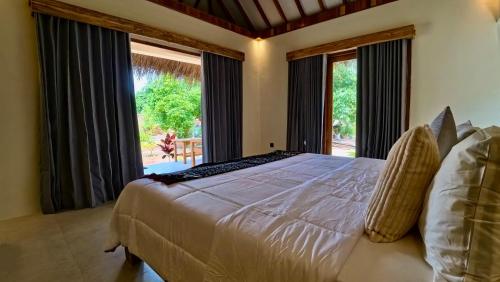 ein Schlafzimmer mit einem großen Bett und einem großen Fenster in der Unterkunft SA Oeona Bungalow in Nembrala
