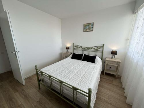 une chambre avec un lit avec des draps blancs et des oreillers noirs dans l'établissement 2 pièces avec balcon, 4 couchages à Saint-Jean-de-Monts - FR-1-224C-319, à Saint-Jean-de-Monts