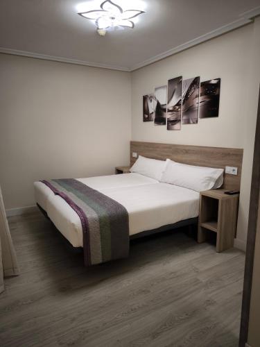 a bedroom with a large white bed and two pictures on the wall at Pensión del Norte in Oviedo