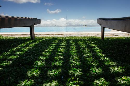 two benches sitting on the grass near the beach at Aetovigla Guesthouse in Krousón