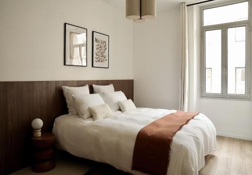 - une chambre dotée d'un grand lit avec des draps blancs et une fenêtre dans l'établissement Somptueux avec grande terrasse, à Cannes