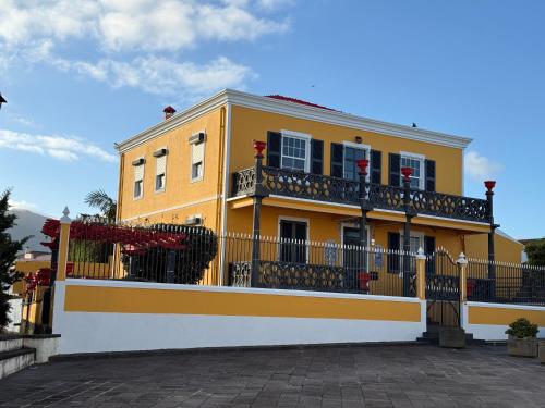a yellow building with a balcony and a fence at Golden Mermaid Villa, Big Home Amenities - Small Hotel Room Price in Ribeira Grande