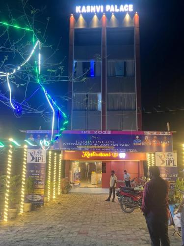 two people walking in front of a building at night at Kashvi Palace in Muzaffarpur
