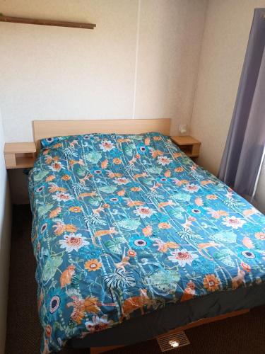 Una cama con un edredón azul con flores. en Static Holiday Caravan, en Clacton-on-Sea