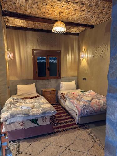 a bedroom with two beds and a chandelier at Auberge restaurant Afoud in Agoudal