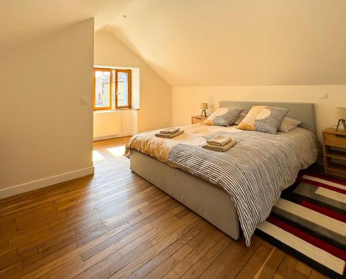 a bedroom with a large bed and a wooden floor at La petite maison in Noyers-sur-Serein