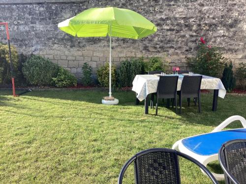 a table with a green umbrella in the grass at Chambre d'hôtes la Maximinoise à 5mn de Chantilly et à proximité de Senlis et autoroute A1,Parc Astérix, Pierrefonds, Compiegne, Aéroport Roissy Charles de Gaulle in Saint-Maximin