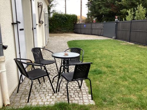 a patio with four chairs and a table in a yard at Chambre d'hôtes la Maximinoise à 5mn de Chantilly et à proximité de Senlis et autoroute A1,Parc Astérix, Pierrefonds, Compiegne, Aéroport Roissy Charles de Gaulle in Saint-Maximin