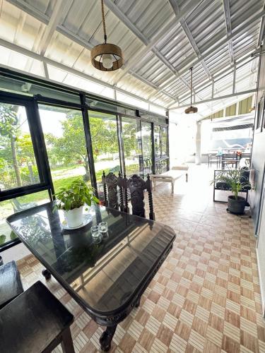 a glass table and chairs in a room with windows at The MIAGE Resthouse in Baliuag