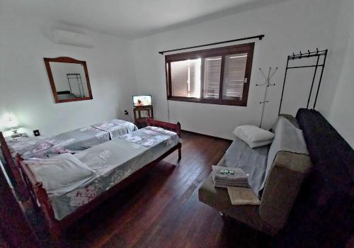 Una sala de estar con dos camas y un sofá en Casa Ampla 2 dormitorios LARANJAL temporada, en Pelotas