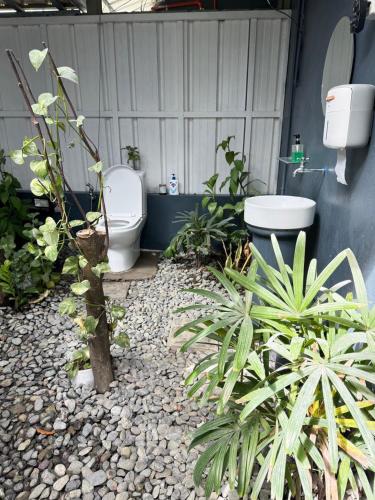 a bathroom with a toilet and some plants at The MIAGE Resthouse in Baliuag
