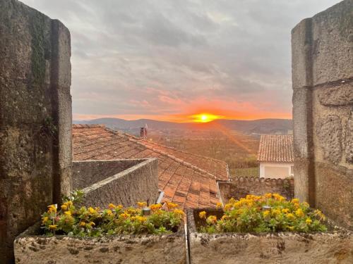 a view of the sunset from an old building with flowers at auberge des trois ami-es in Vinezac