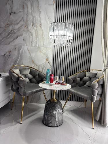 a room with two chairs and a table and a chandelier at R U B I room by 50 shades in Baia Mare