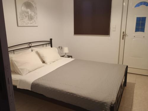a bed with white sheets and pillows in a bedroom at Nikitas apartment 2 in (( Kermetés ))