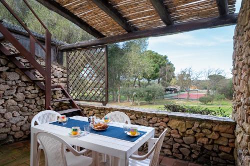una mesa blanca y sillas en un patio con una pared de piedra. en Caletta Nest 38, en Porto Rotondo