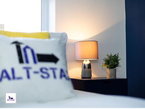 a lamp sitting on a table next to a bed at Carnforth by Alt-Stay - Wakefield 2 Bed Ensuite Townhouse Contractor and Corporate Accommodation with Private Balcony, Parking, Smart TV, Kitchen and Fast Wi Fi - Long Stay Ready with Weekly and Monthly Rates in Wakefield