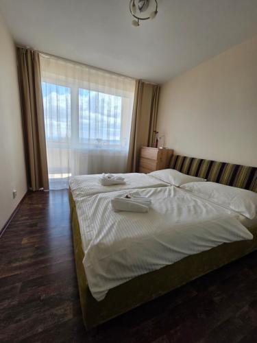 a large bed in a bedroom with a large window at Apartment High Tatras in Veľký Slavkov