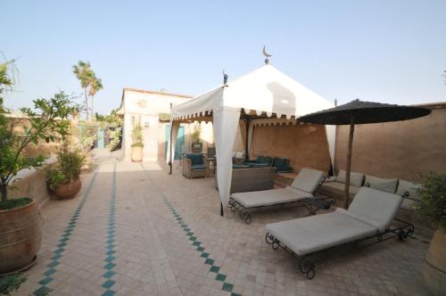 a patio with a gazebo and chairs and an umbrella at Palais Oumensour in Taroudant