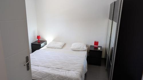 une petite chambre avec un lit avec des draps blancs et des oreillers dans l'établissement Gite El PACHA II 4 etoiles pres d'argeles sur mer au calme au pied des montagnes, à Laroque-des-Albères