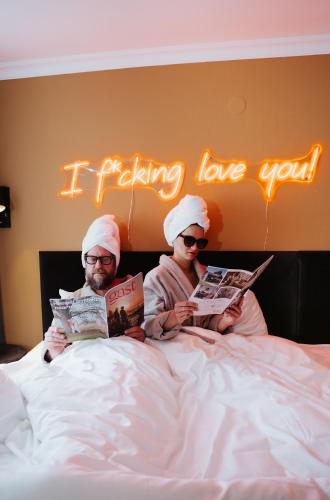 two people sitting on a bed reading a book at Hotel Janssen in Valkenburg
