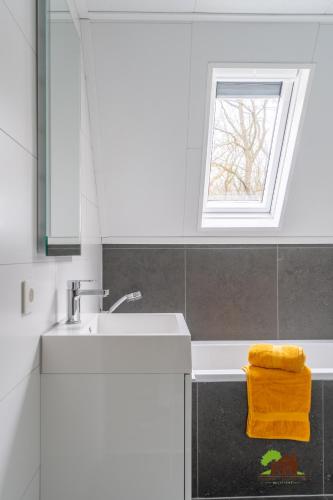 a white bathroom with a sink and a window at Touch of Yellow in Gramsbergen