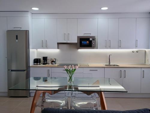 una cocina con una mesa de cristal con un jarrón de flores en Balcon mirador de las Salinas, en Sanlúcar de Barrameda