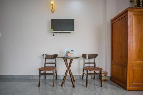 a table with two chairs and a tv on a wall at P Xuân Quy Nhơn Hotel in Quy Nhon
