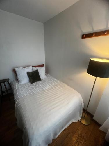 une chambre avec un lit avec des draps blancs et une lampe dans l'établissement Appartement Parisian Chic, à Paris