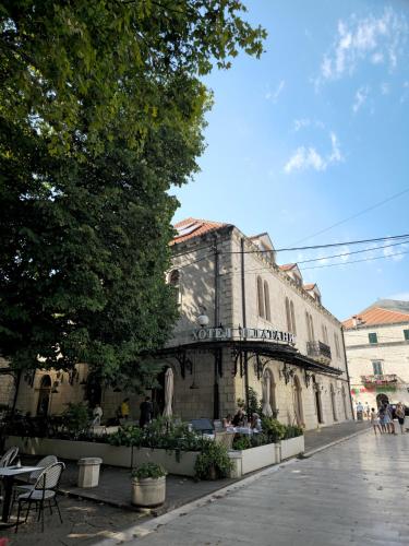 an old building with people sitting outside of it at Apartman Platani in Trebinje