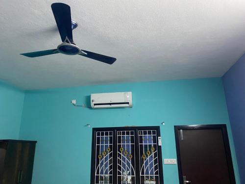 a ceiling fan in a room with a blue wall at Lakeside Home Stay Villa in Yelagiri
