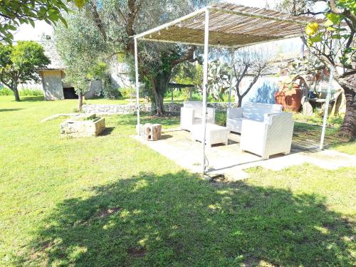 a gazebo with white furniture in a park at Masseria Li Camerini in Vanze